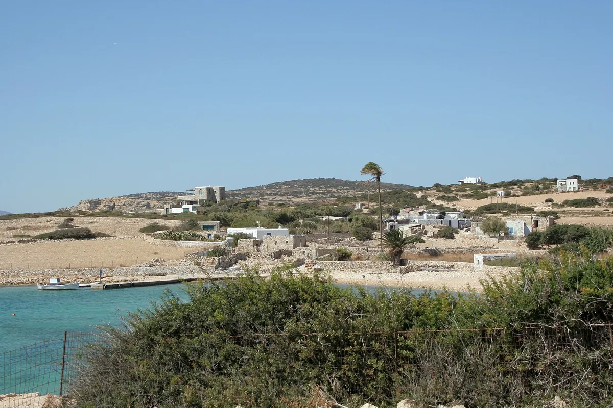 Whitewash houses and a beach on Kato Koufonisi island seen across calm water, Small Cyclades, Greece