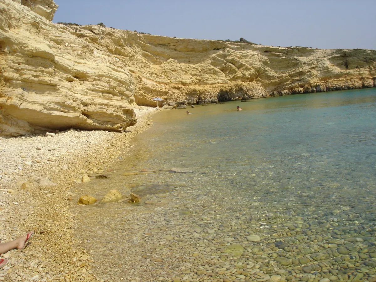 Golden rocky cove with pebble sand and clear green water at Kato Koufonisi island in the Small Cyclades