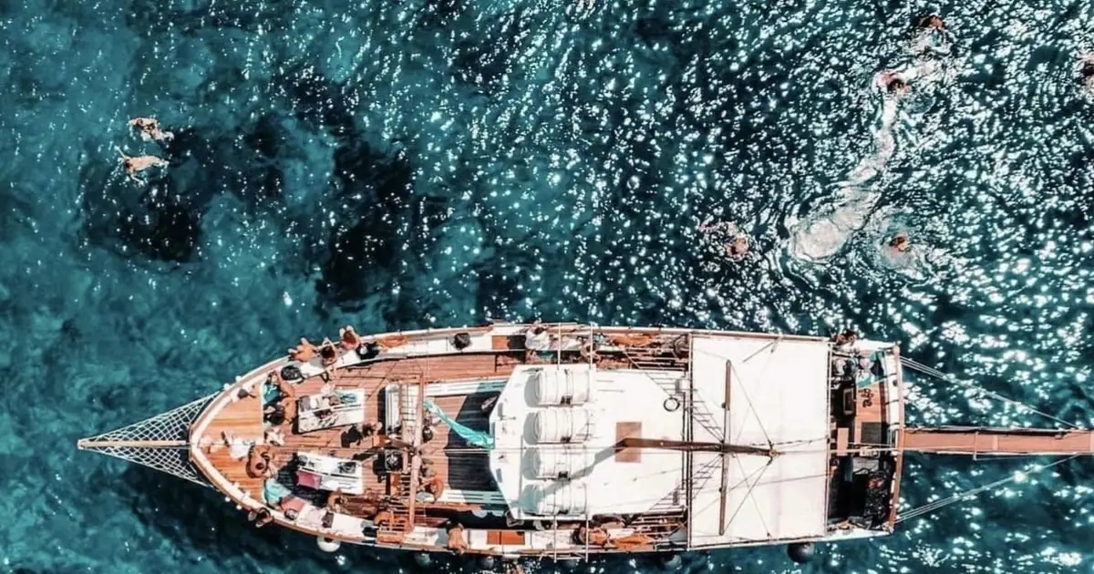 Traditional wooden Greek cruise boat anchored off a turquoise Koufonisia beach on a full-day Naxos boat tour to the Small Cyclades